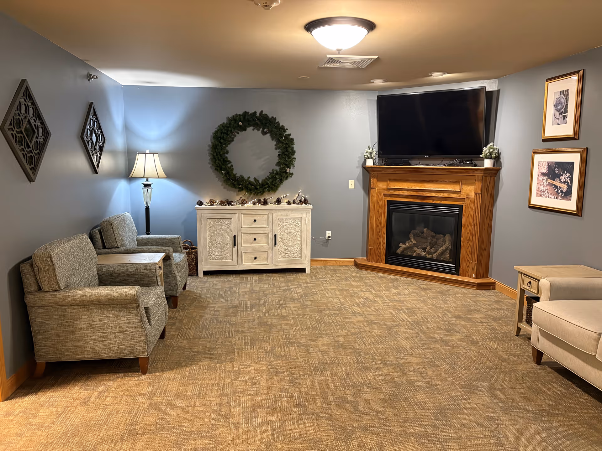 Cozy living room with blue walls, seating, a fireplace, and a mounted television.