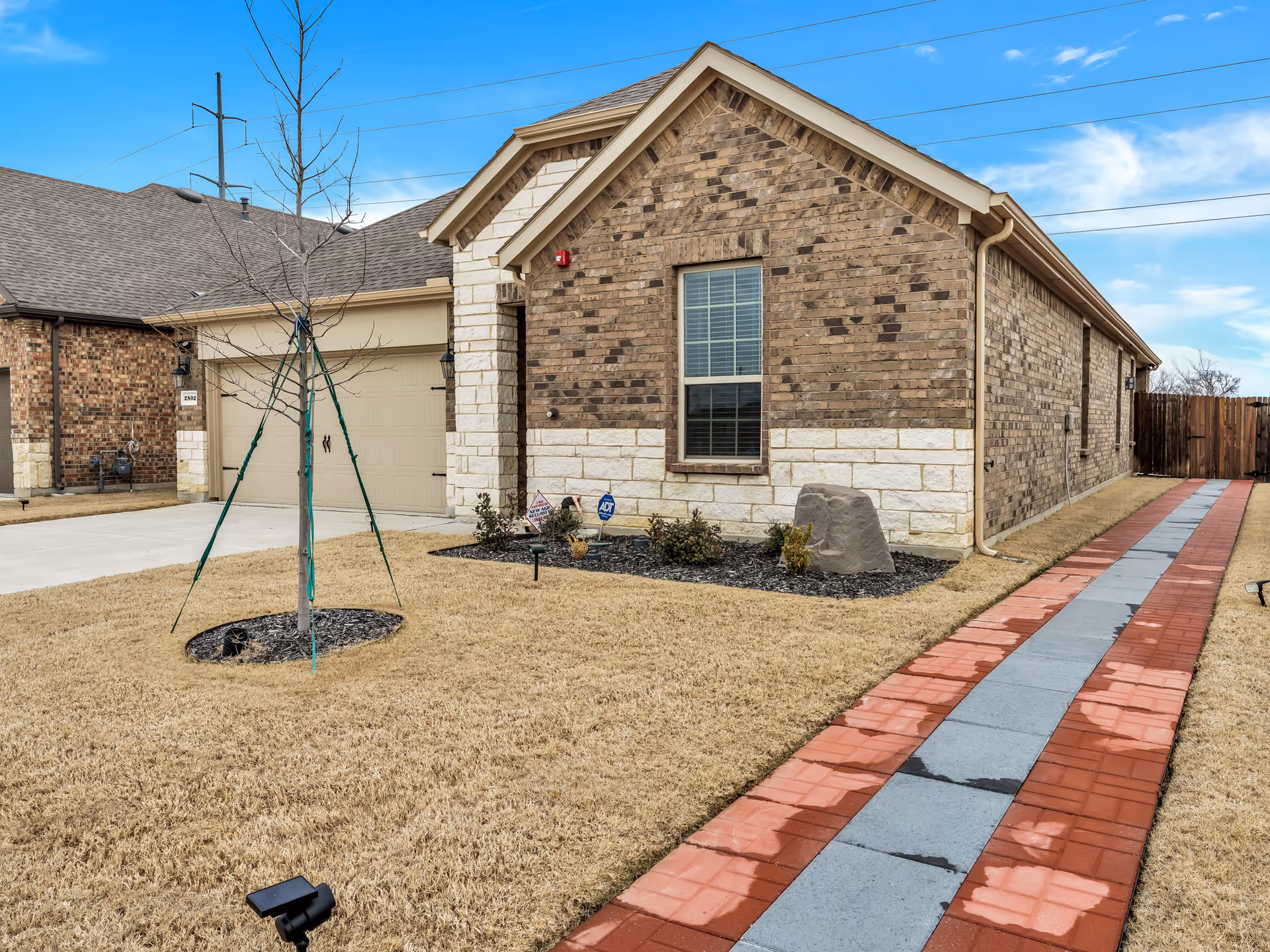 Assisted living facility exterior in brick, with a paved walkway and small yard.