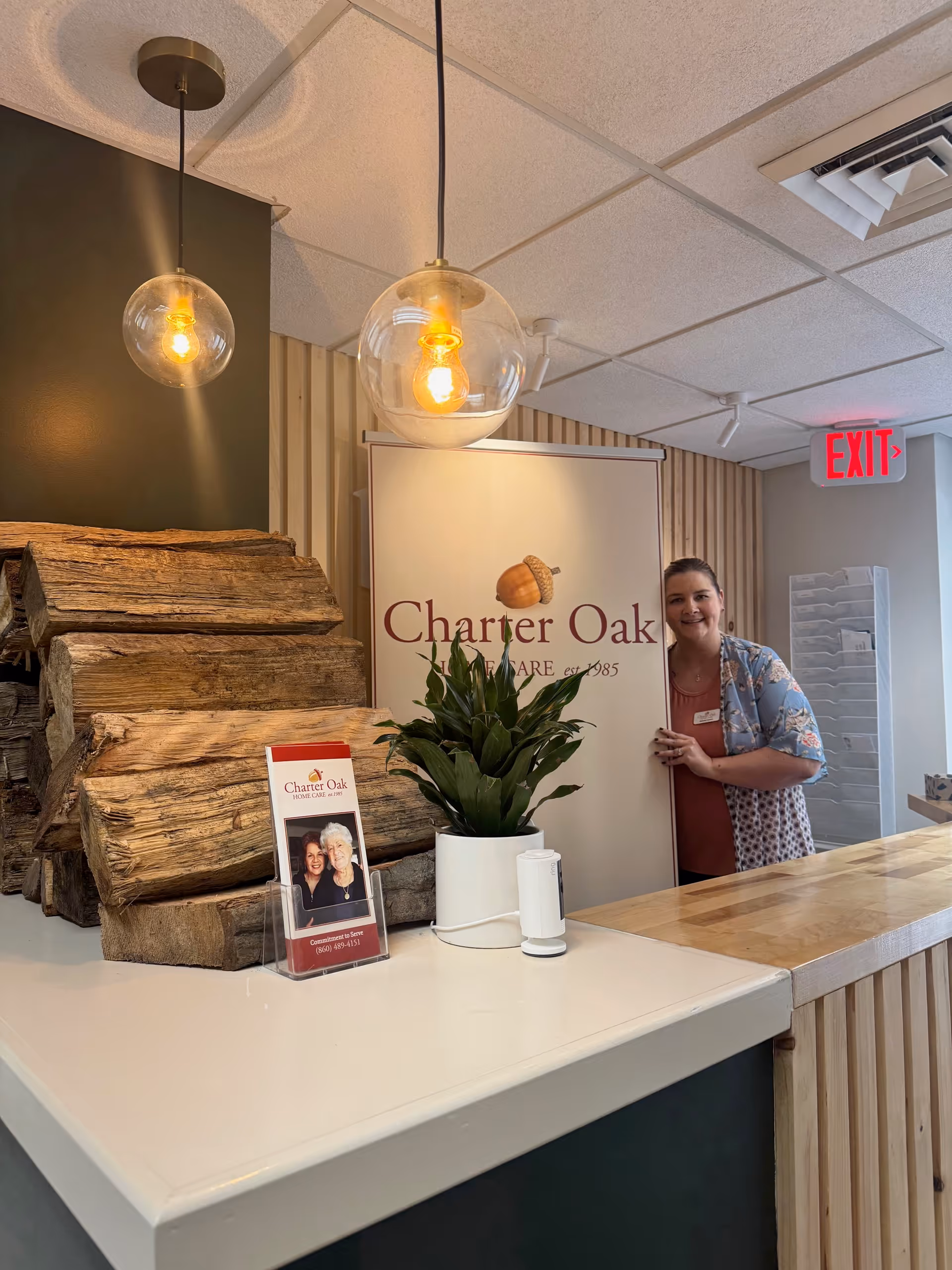 Reception area at Charter Oak Home Care with staff beside a log display and plant.