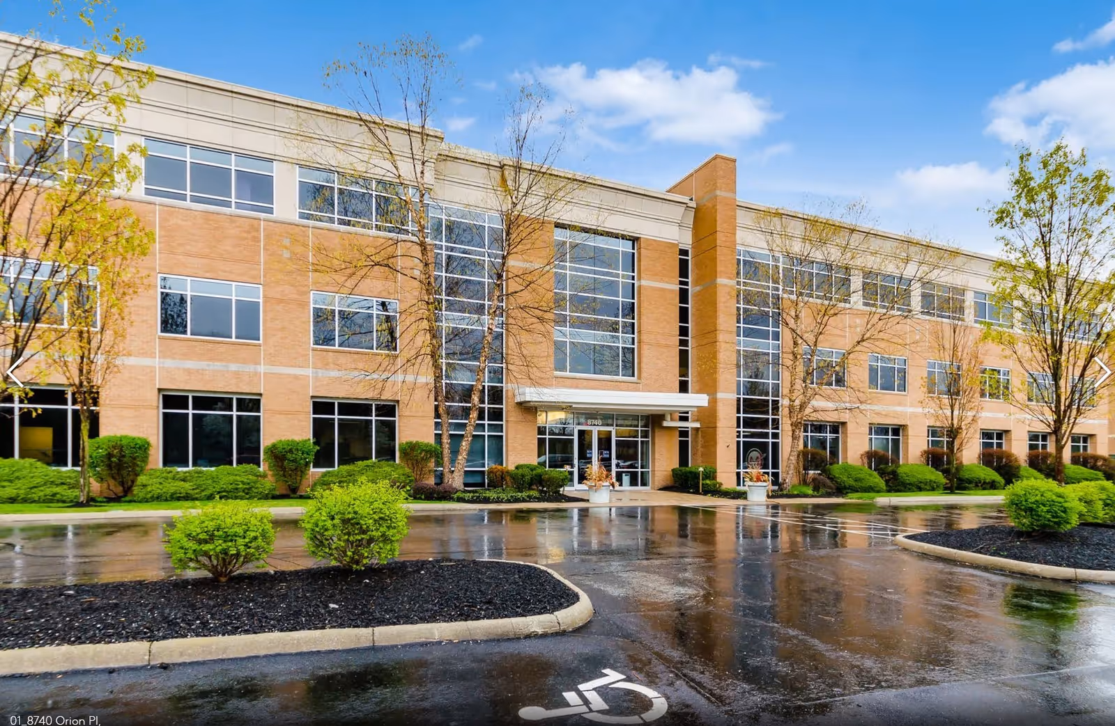 Front view of a brick senior care facility with glass entrance and landscaping