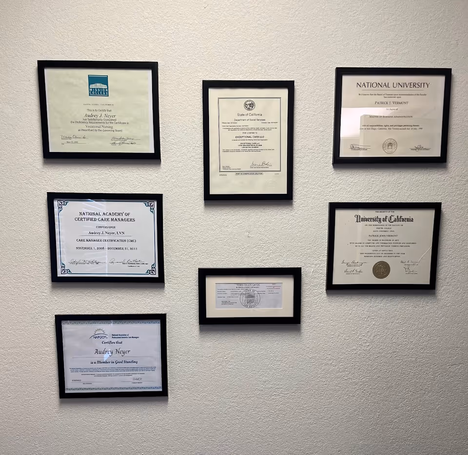 Wall of framed certificates displayed in a facility hallway.