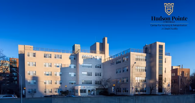 Exterior view of a multi-story senior living facility with a logo in the top-right corner