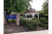 Front view of Church of God Home with sign, gazebo, and landscaped entrance.