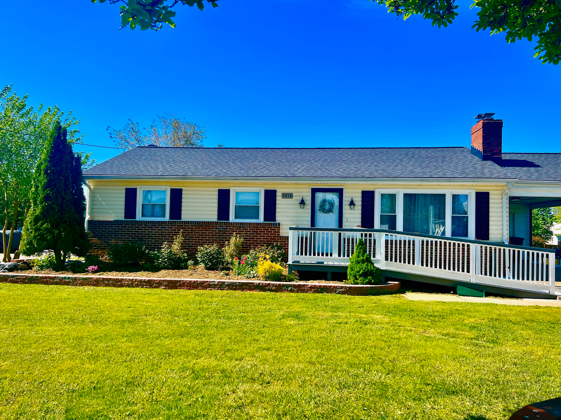 Single-story residential-style building with white siding, brick accent, and a front porch with ramp.