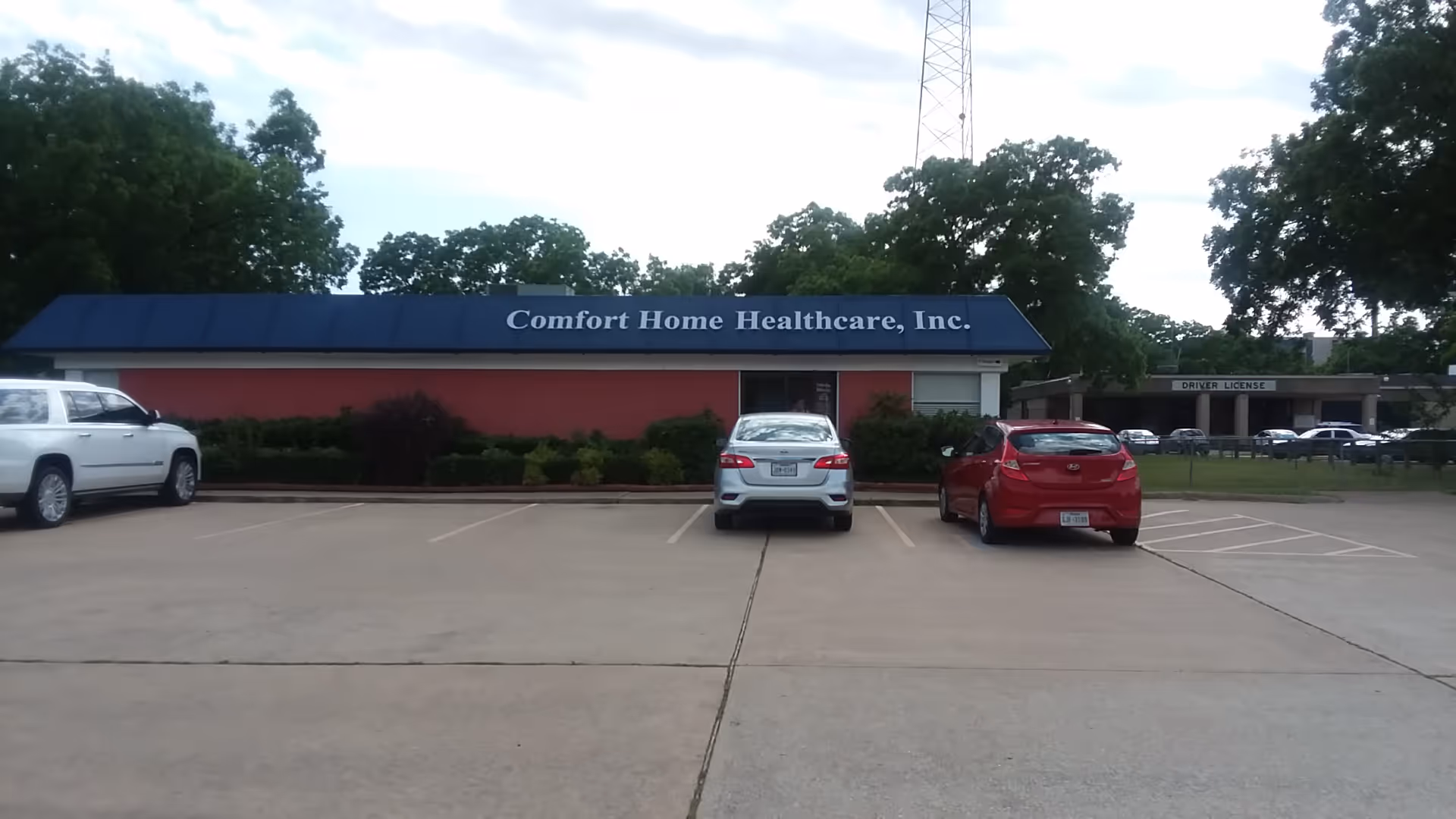 Exterior view of Comfort Home Healthcare facility with blue-roofed building and parked cars