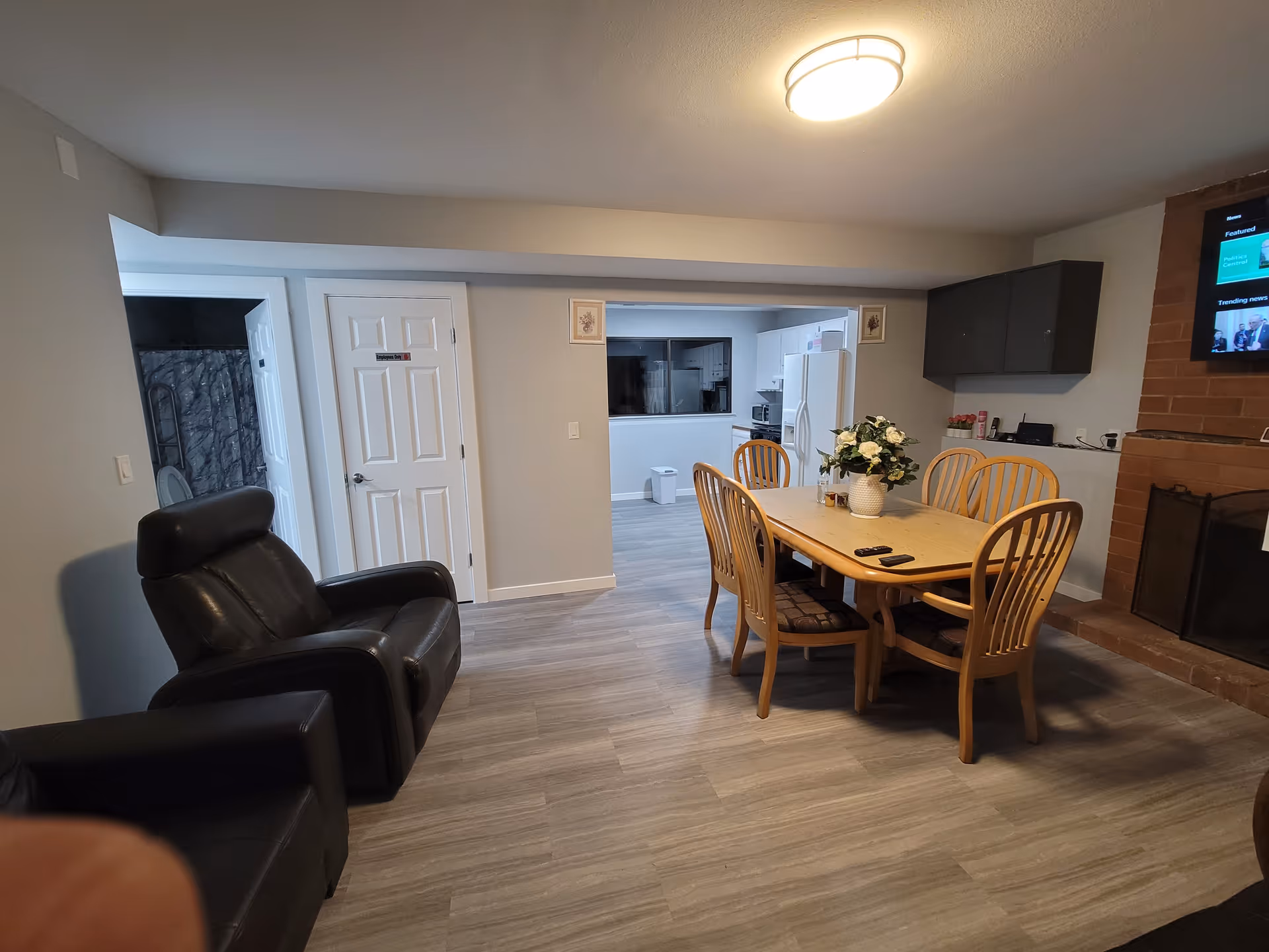Open living and dining area with a wooden table, chairs, and a fireplace.