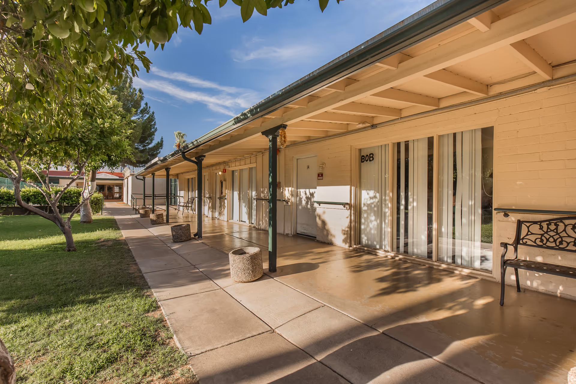 Covered exterior walkway of a Maryland Gardens Post Acute building with glass doors and benches.