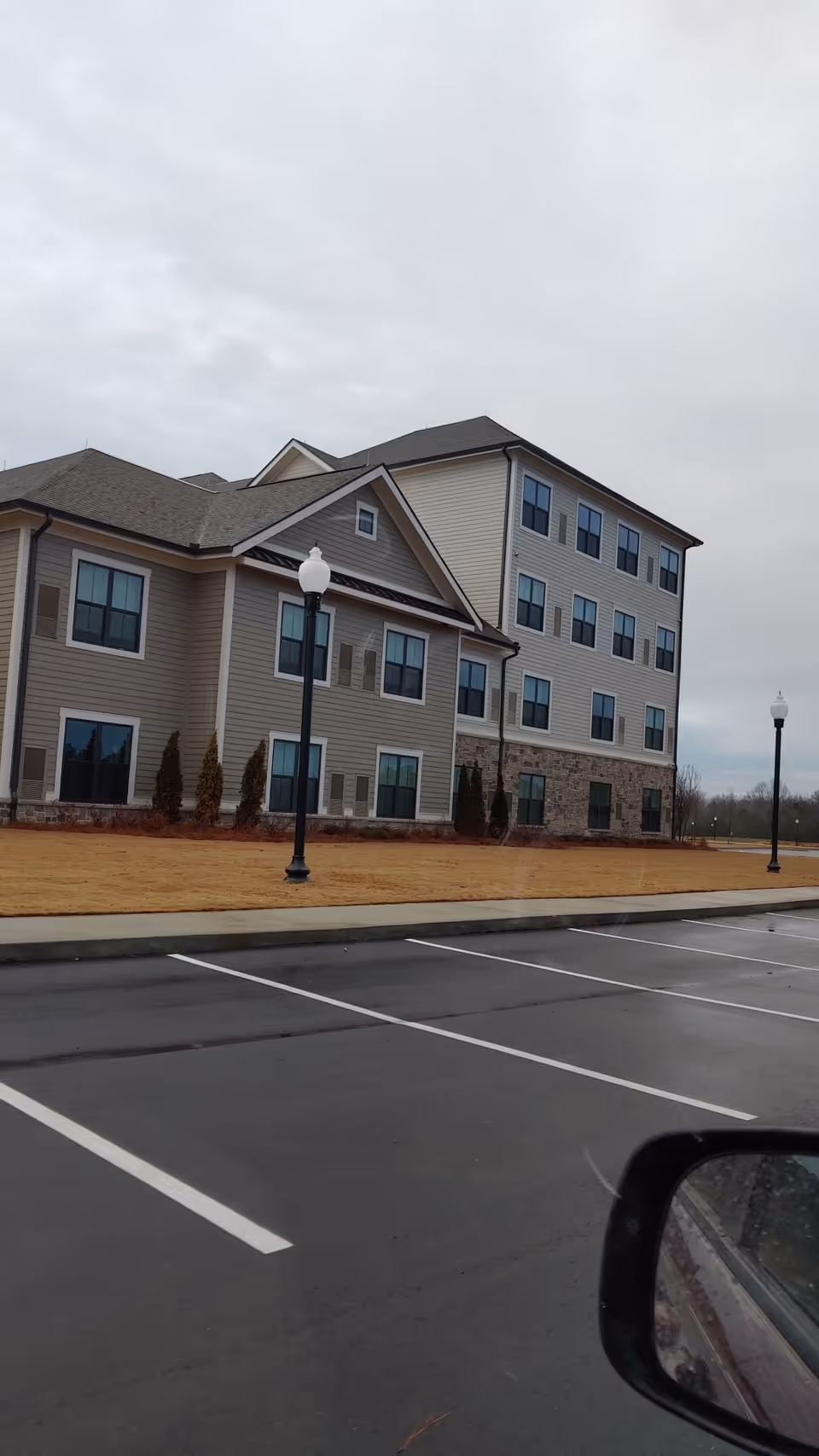 Exterior view of a two-story senior living building with a parking lot and street lamps.