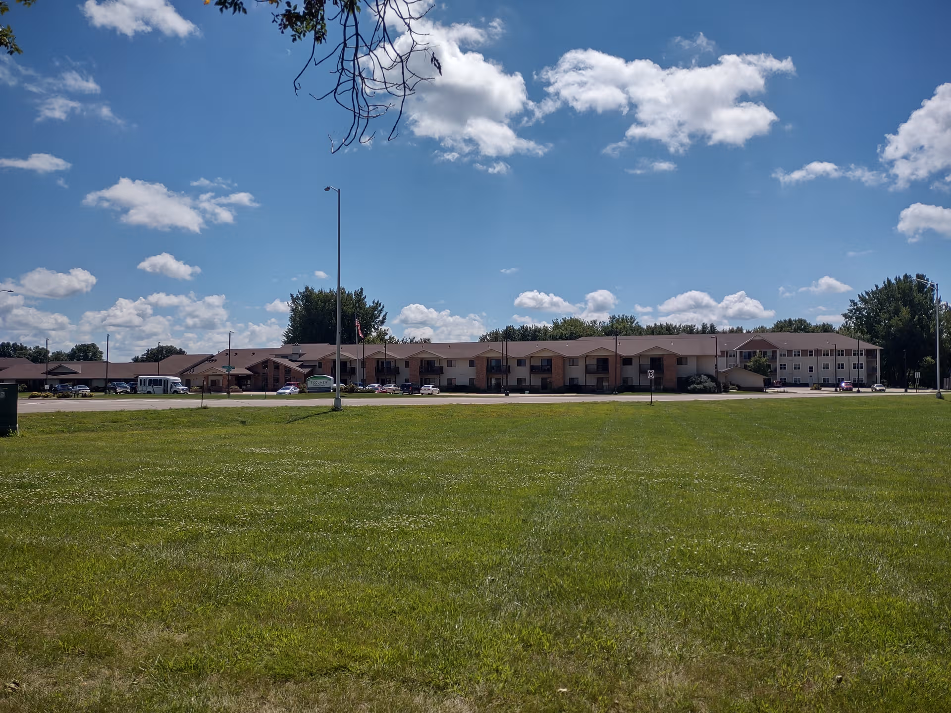 Wide view of Ecumen Meadows exterior building with a grassy foreground under blue sky.