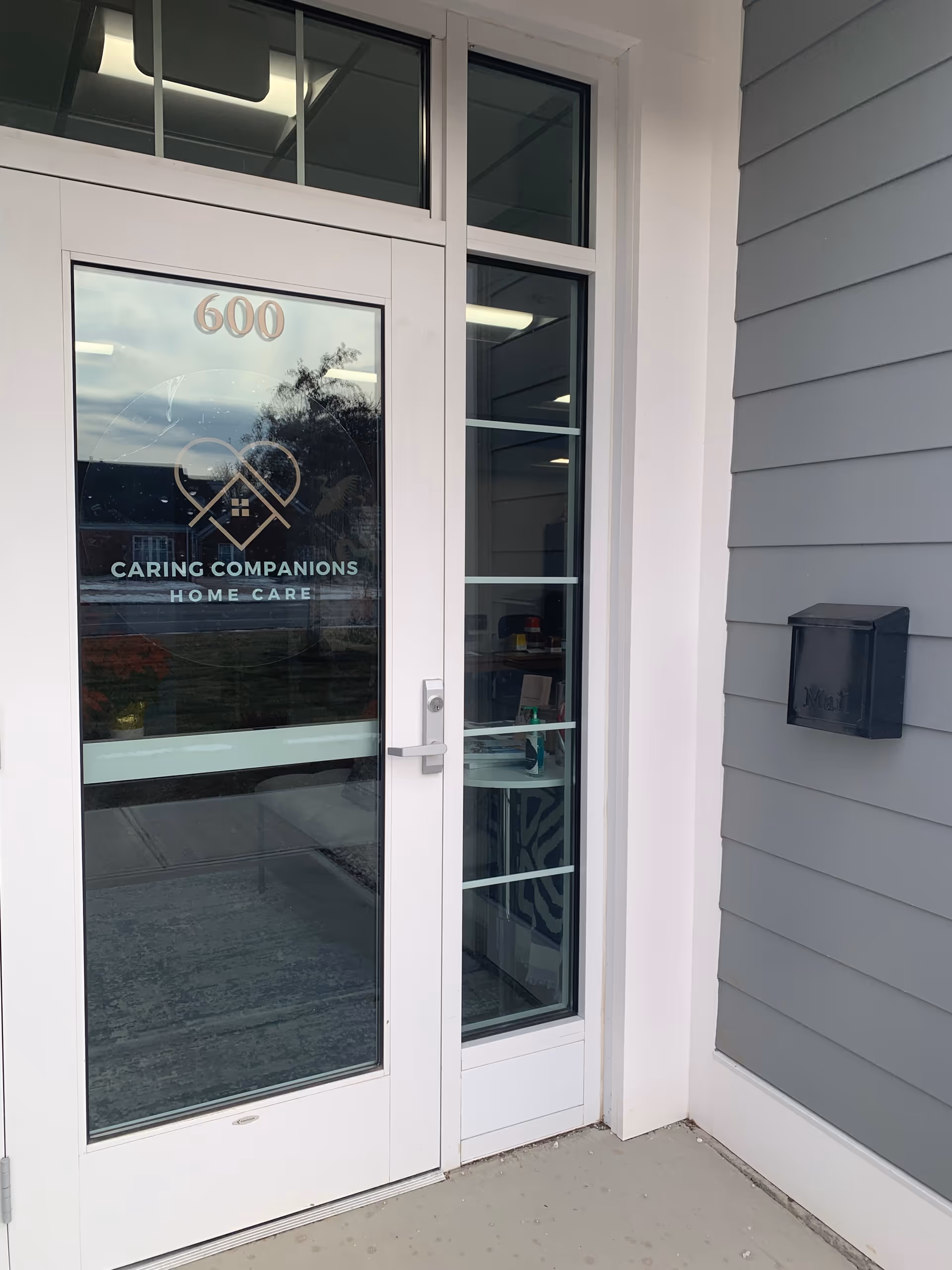 White-framed glass door entrance displaying Caring Companions Home Care logo and 600.