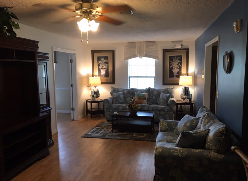 Cozy living room with blue-patterned sofas, two lamps, and a central coffee table.