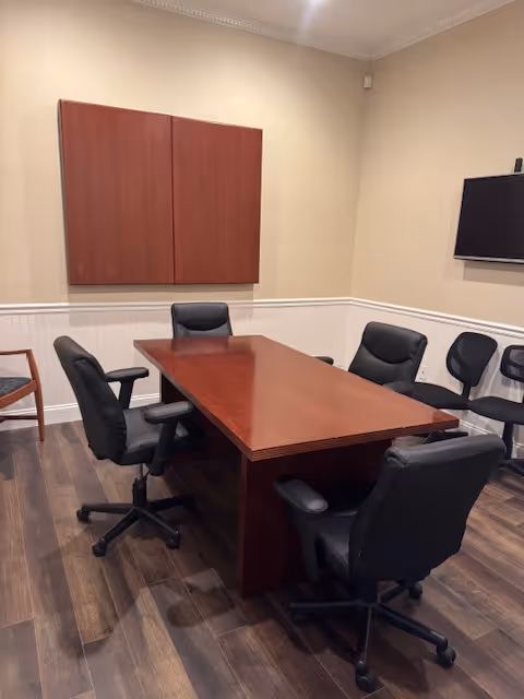 A conference room with a wooden table and black office chairs.