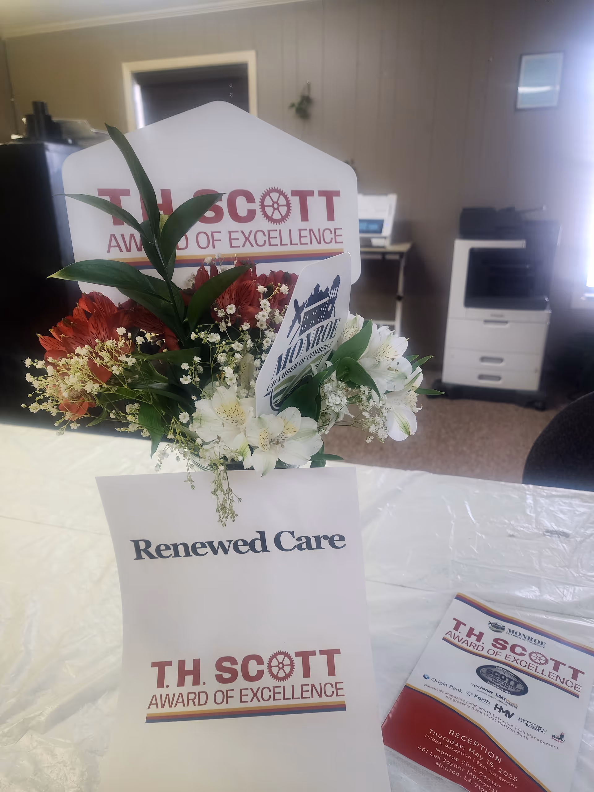 Bouquet and award cards displayed on a desk inside a facility's interior.