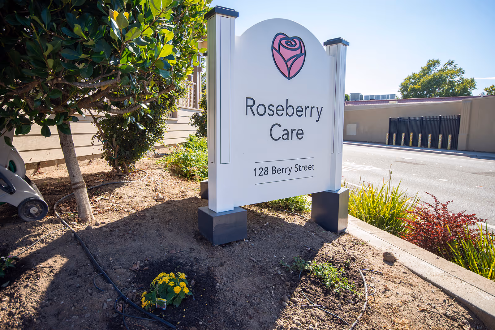 Exterior sign reading Roseberry Care at the facility entrance with landscaping and street view.