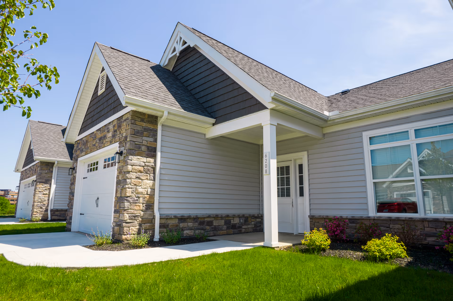 A modern senior living facility with stone accents and a covered entrance beside a green lawn.
