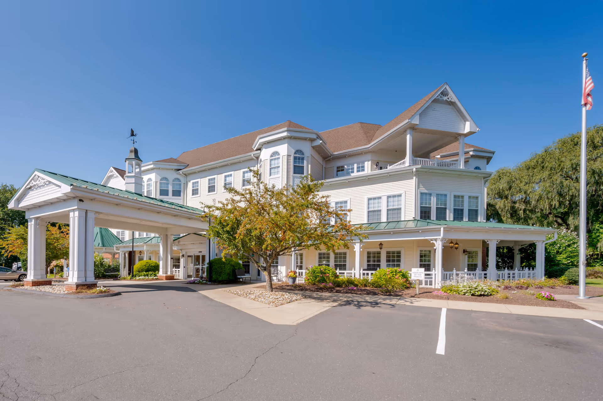 A large white three-story senior living facility with a covered entrance and landscaped grounds.