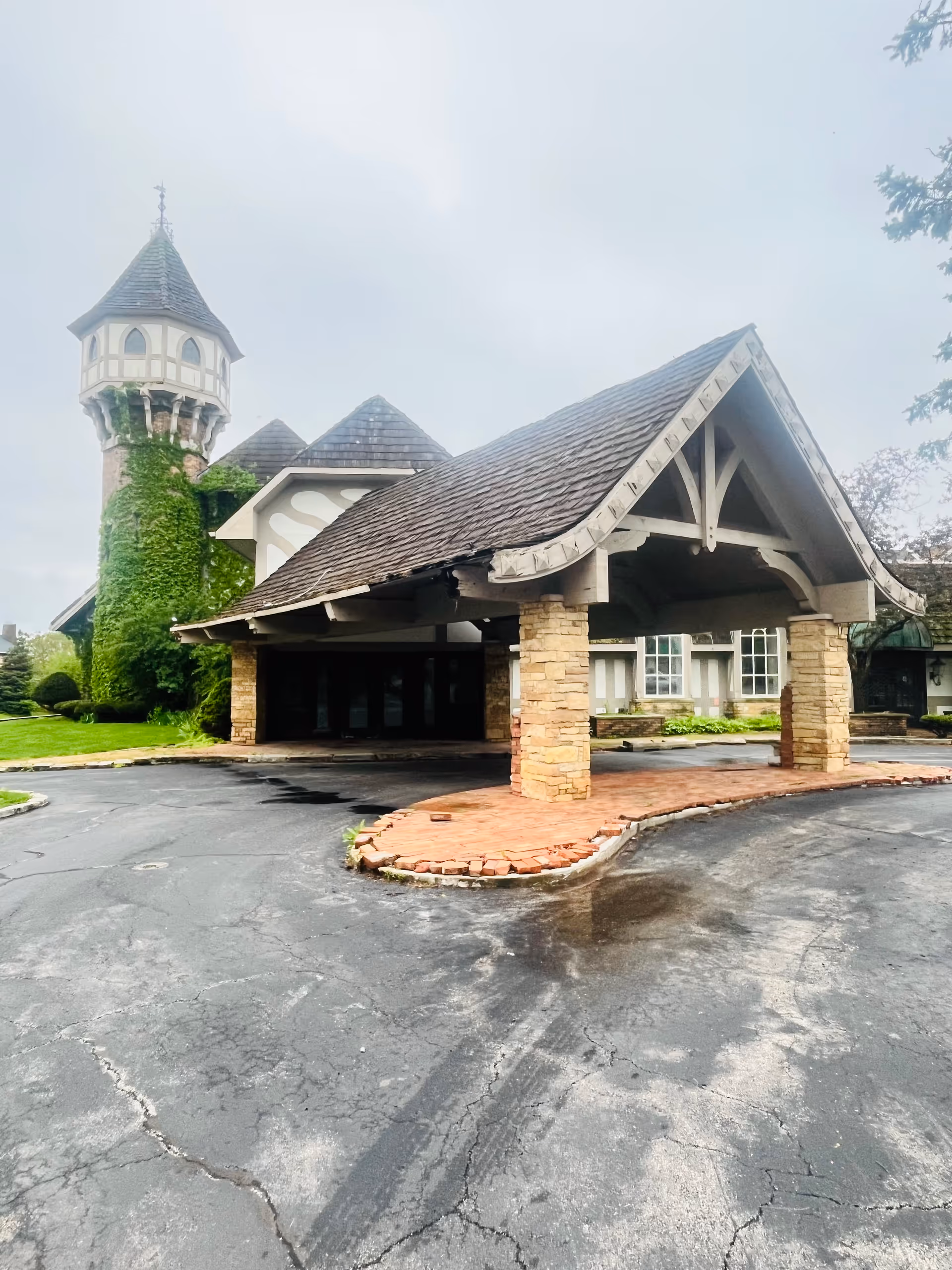 Exterior of a senior living facility with a stone porte-cochere and ivy-covered tower.