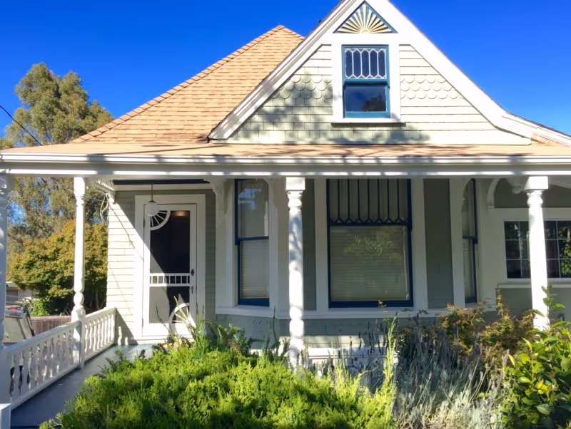 A single-story house with a covered porch, decorative columns, and a front garden.