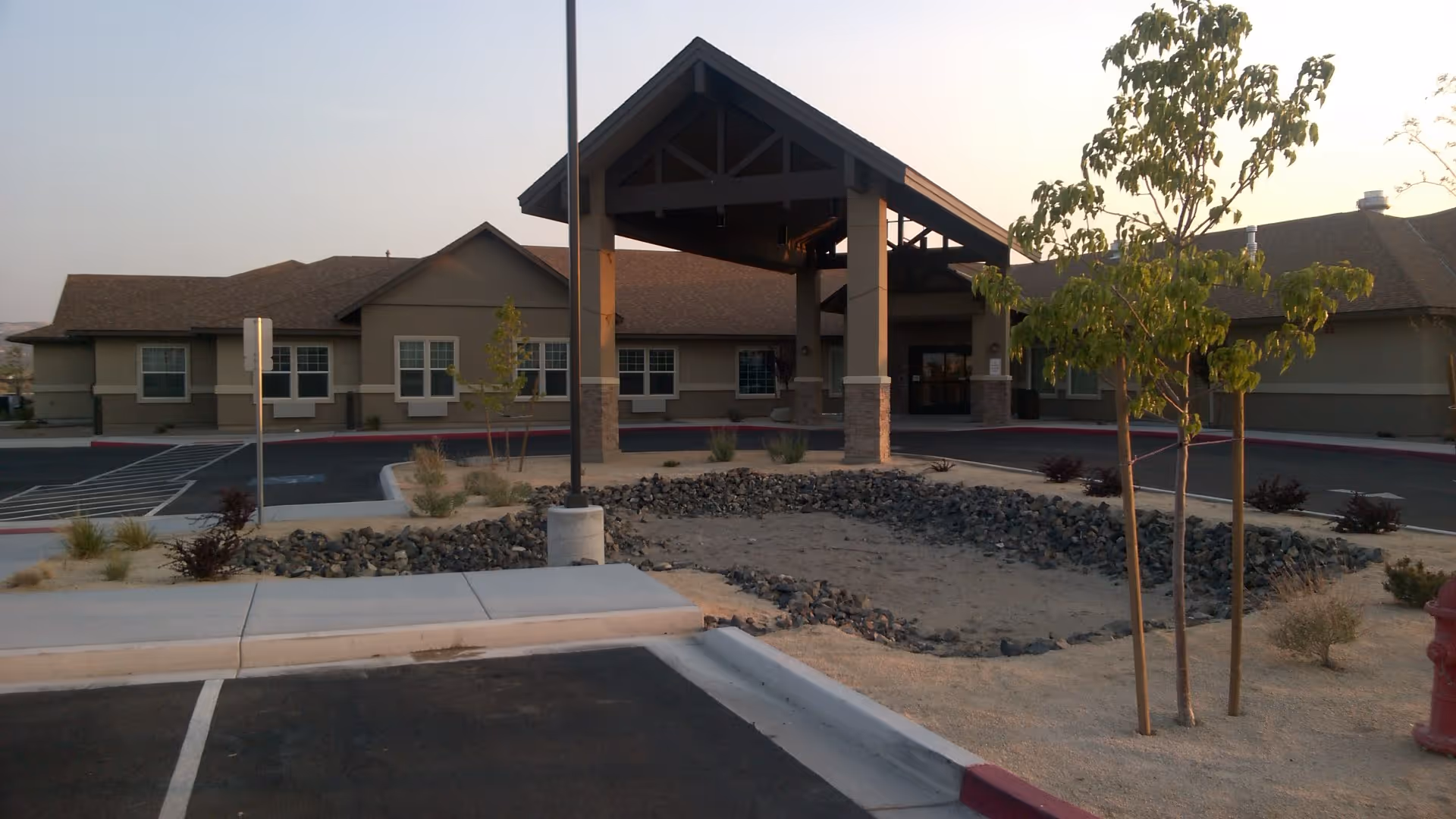 Senior living facility entrance with a covered porte-cochère and adjacent parking lot.