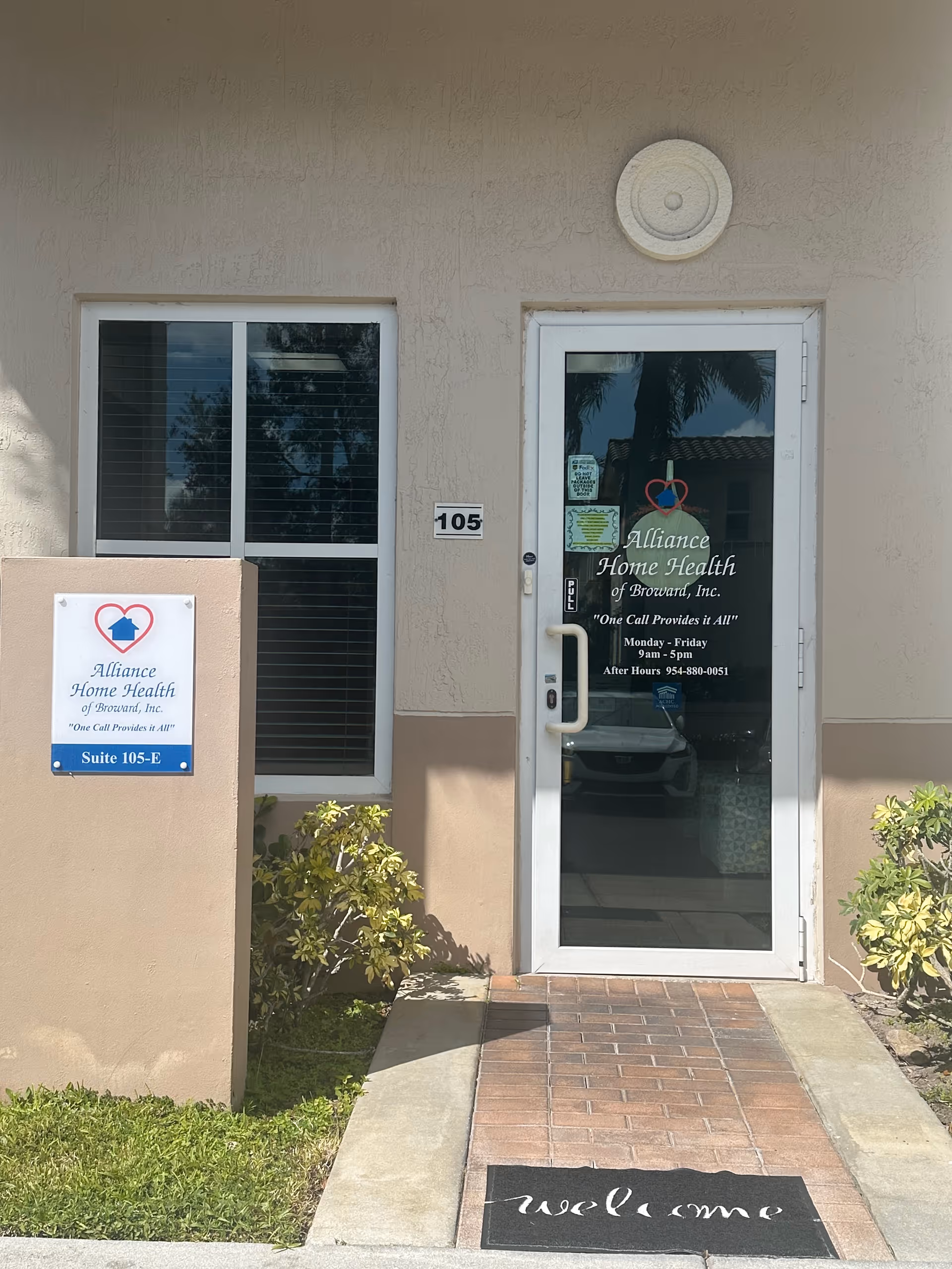 Exterior entrance to Alliance Home Health of Broward, Inc., glass door with signage on beige building.
