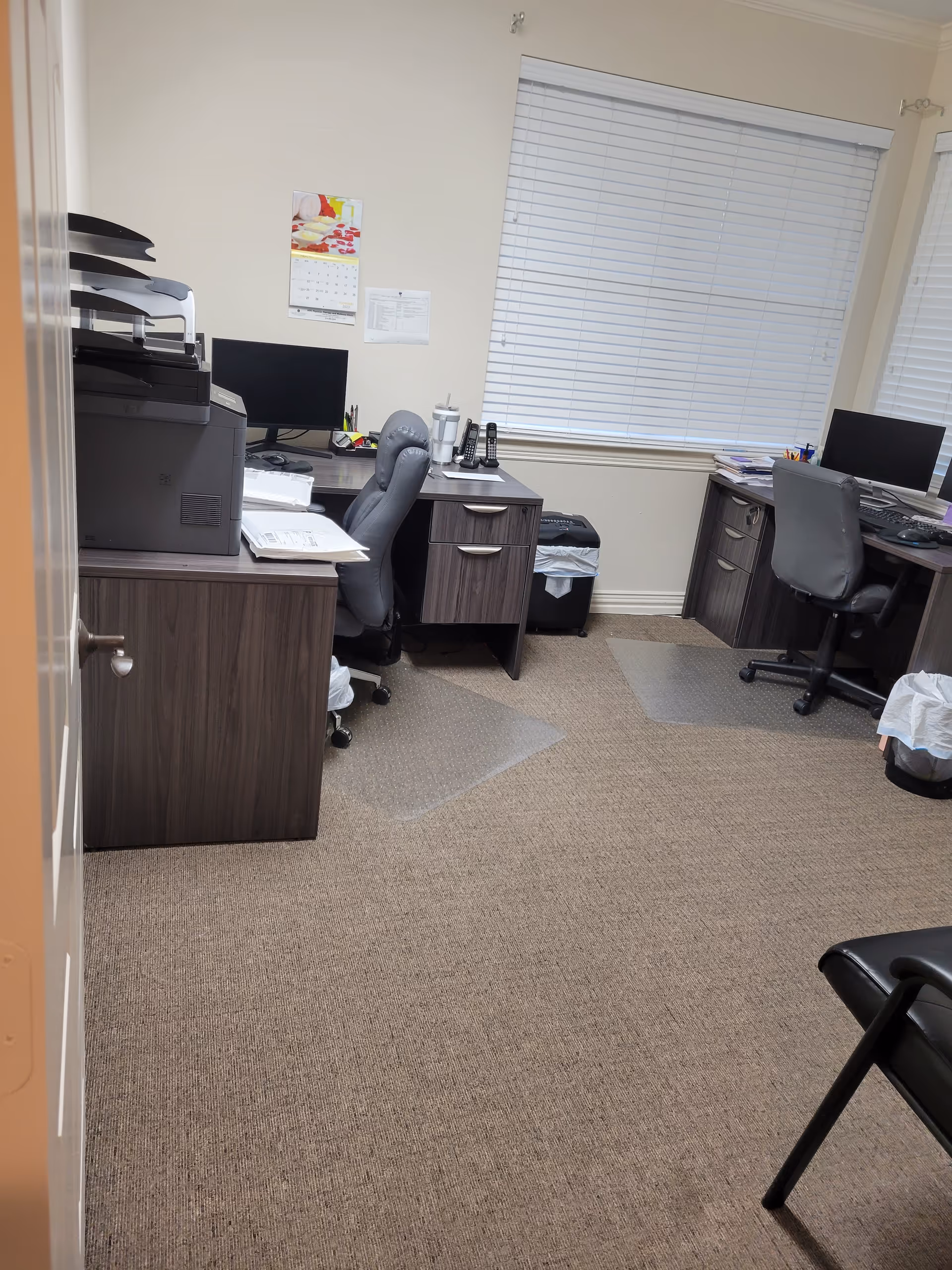 Office workspace with desks, computers, and a printer in a facility.