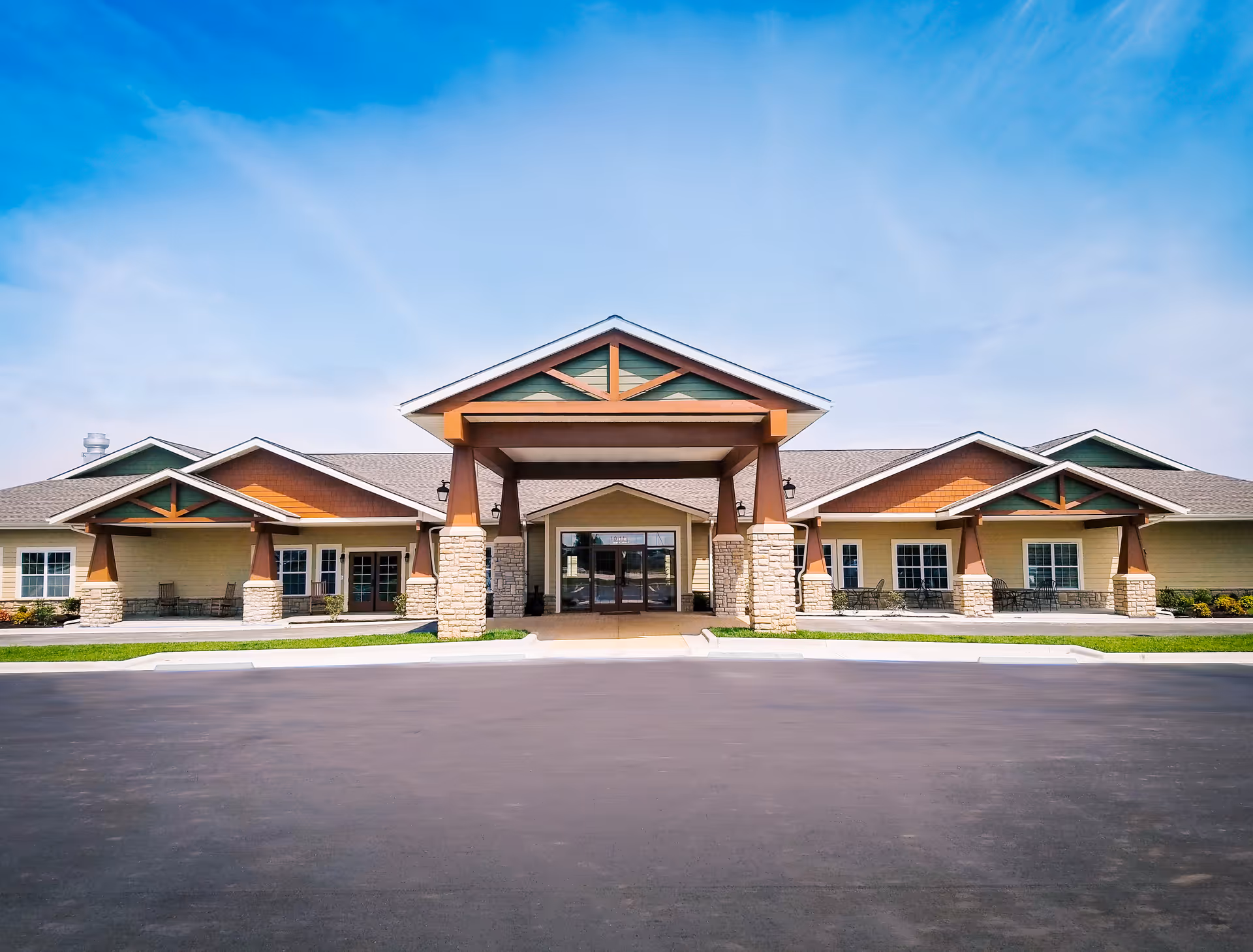 Front view of a modern senior living facility with stone columns and a covered entrance.