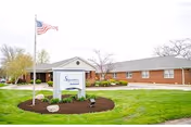 Front exterior of Signature HealthCARE at Parkwood with lawn, sign, and flag