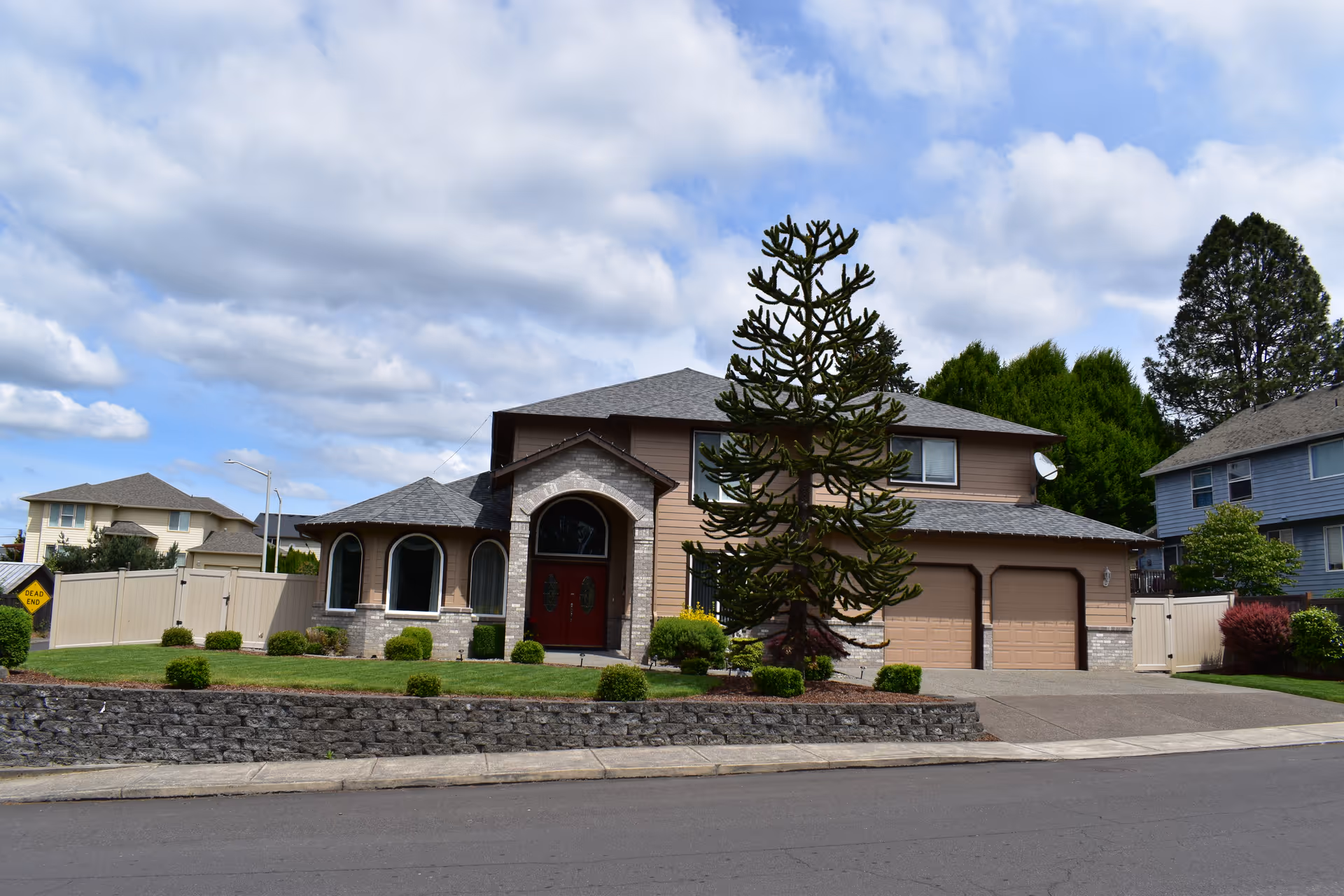 Front view of a two-story house with arched entry and attached two-car garage.