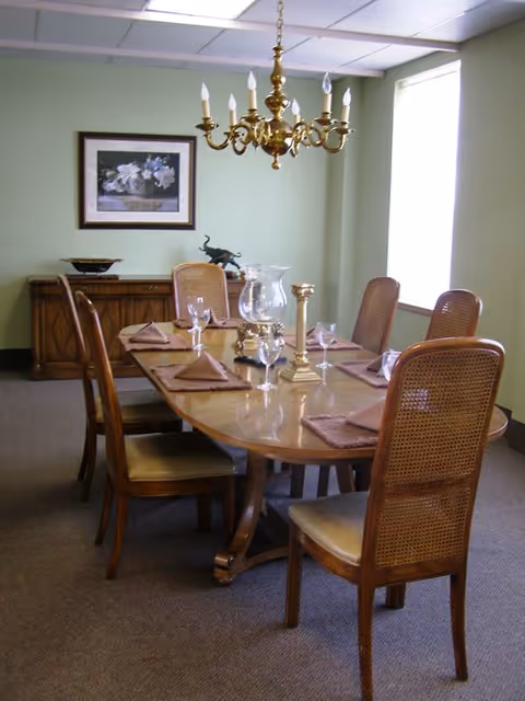 A dining room in Cambridge Court with a long wooden table, chandelier, and chairs.