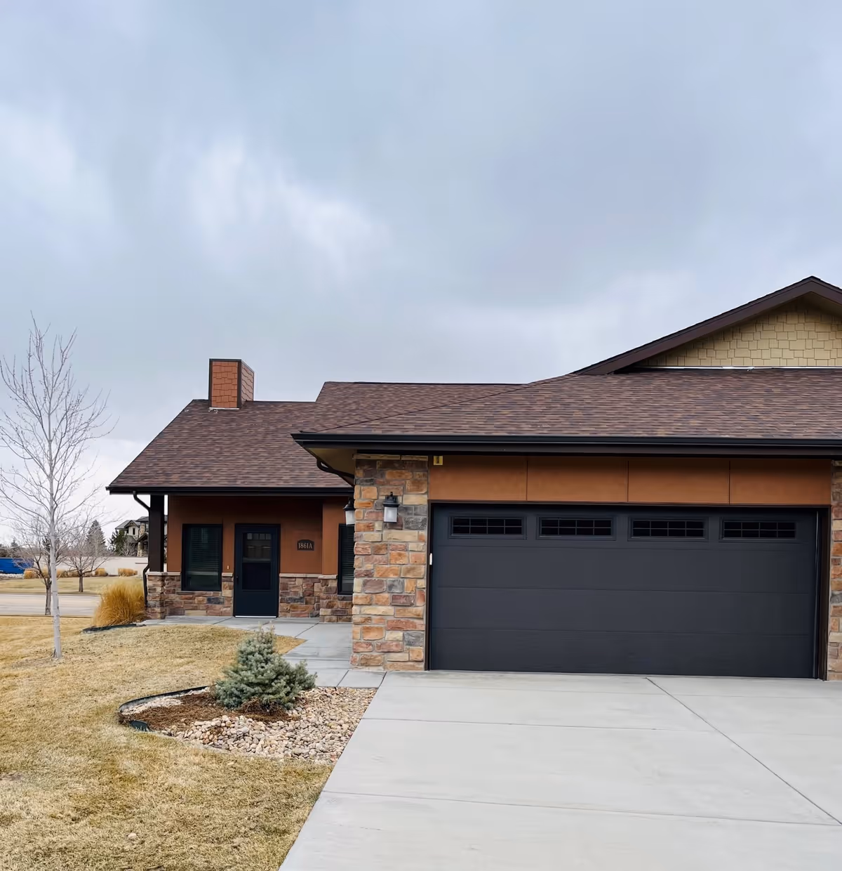 Modern single-story facility exterior with stone façade, dark garage door, and manicured front yard.