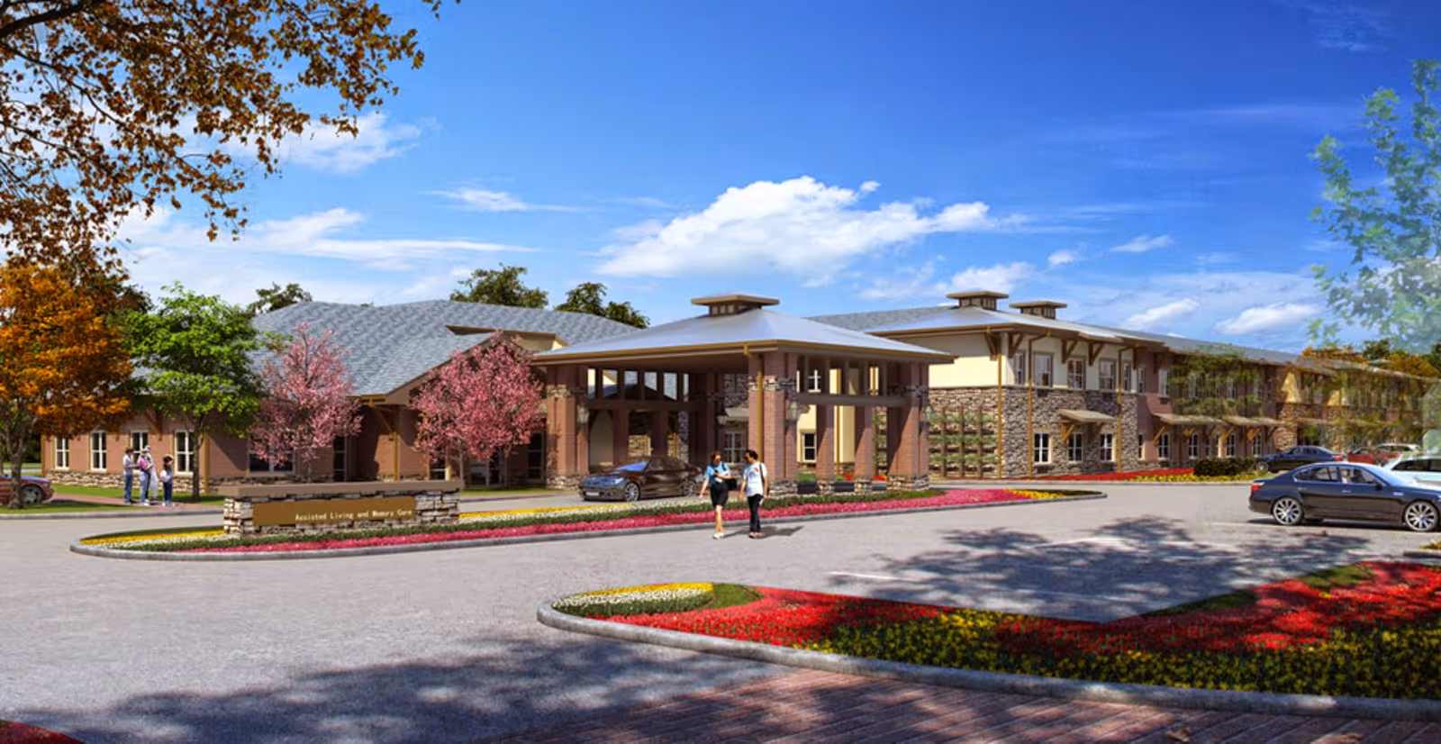 Exterior view of Cedar Bluff Assisted Living & Memory Care facility with a large covered entrance, landscaped flower beds, trees with autumn and pink blossoms, and several parked cars. Two people are walking near the entrance under a blue sky with scattered clouds.