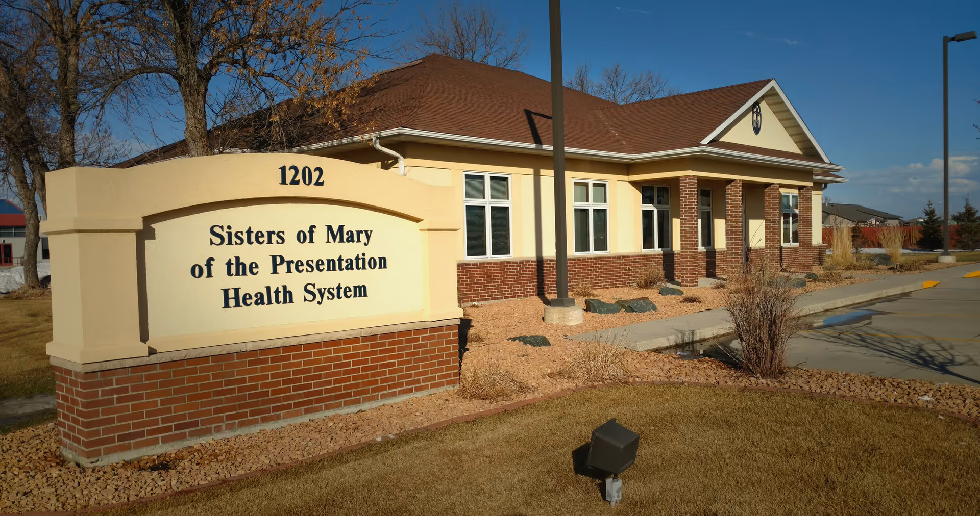 Exterior view of SMP Health facility with a large sign and brick facade.