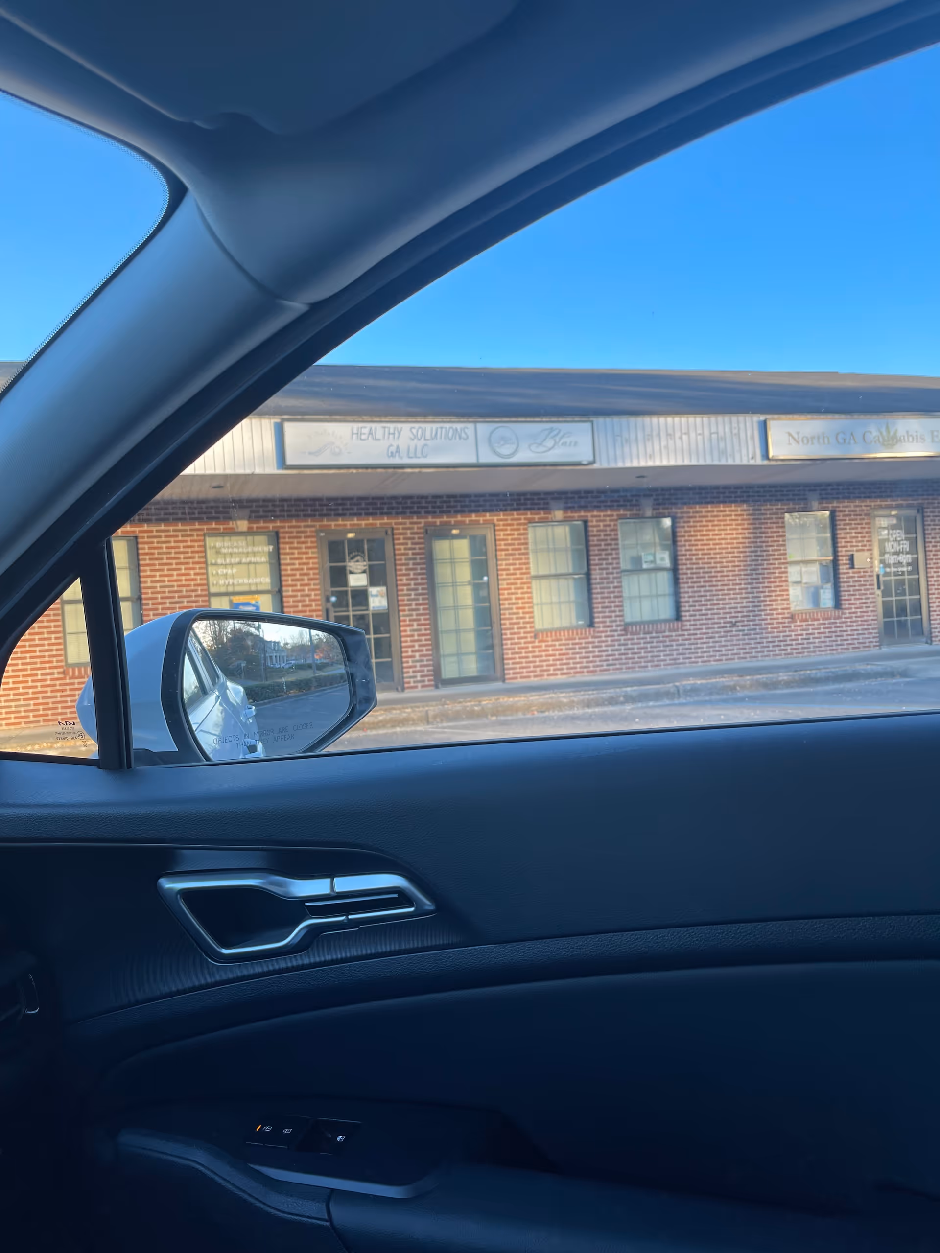 View from inside a car shows a brick storefront labeled Healthy Solutions GA LLC.