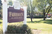 Exterior view of a Fairhaven sign with lawn, trees, and a building.