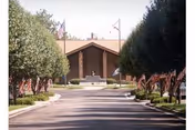 The front exterior of Air Force Enlisted Village with a driveway and flags.
