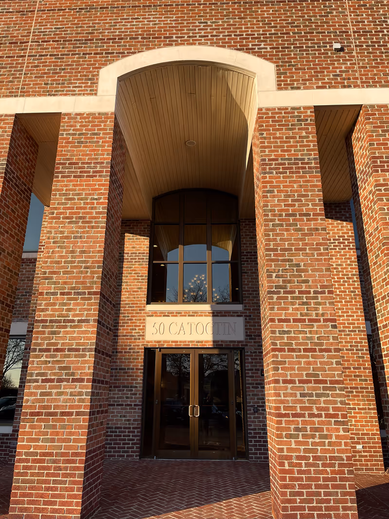 Brick building entrance with arched doorway and glass doors.