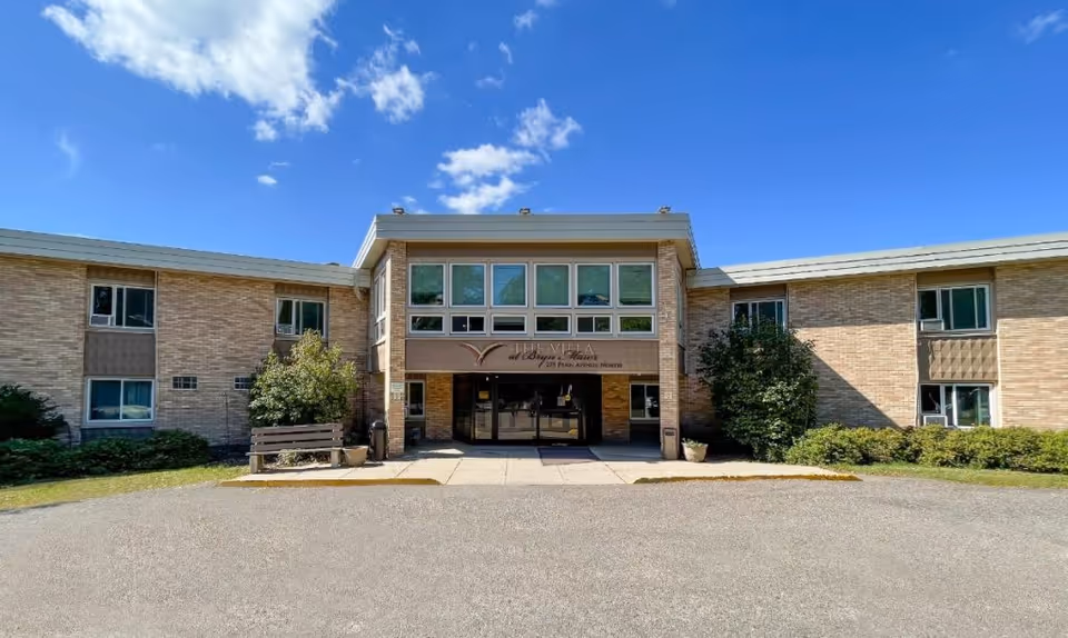 Exterior view of The Villa at Bryn Mawr, brick building with glass entry and blue sky.