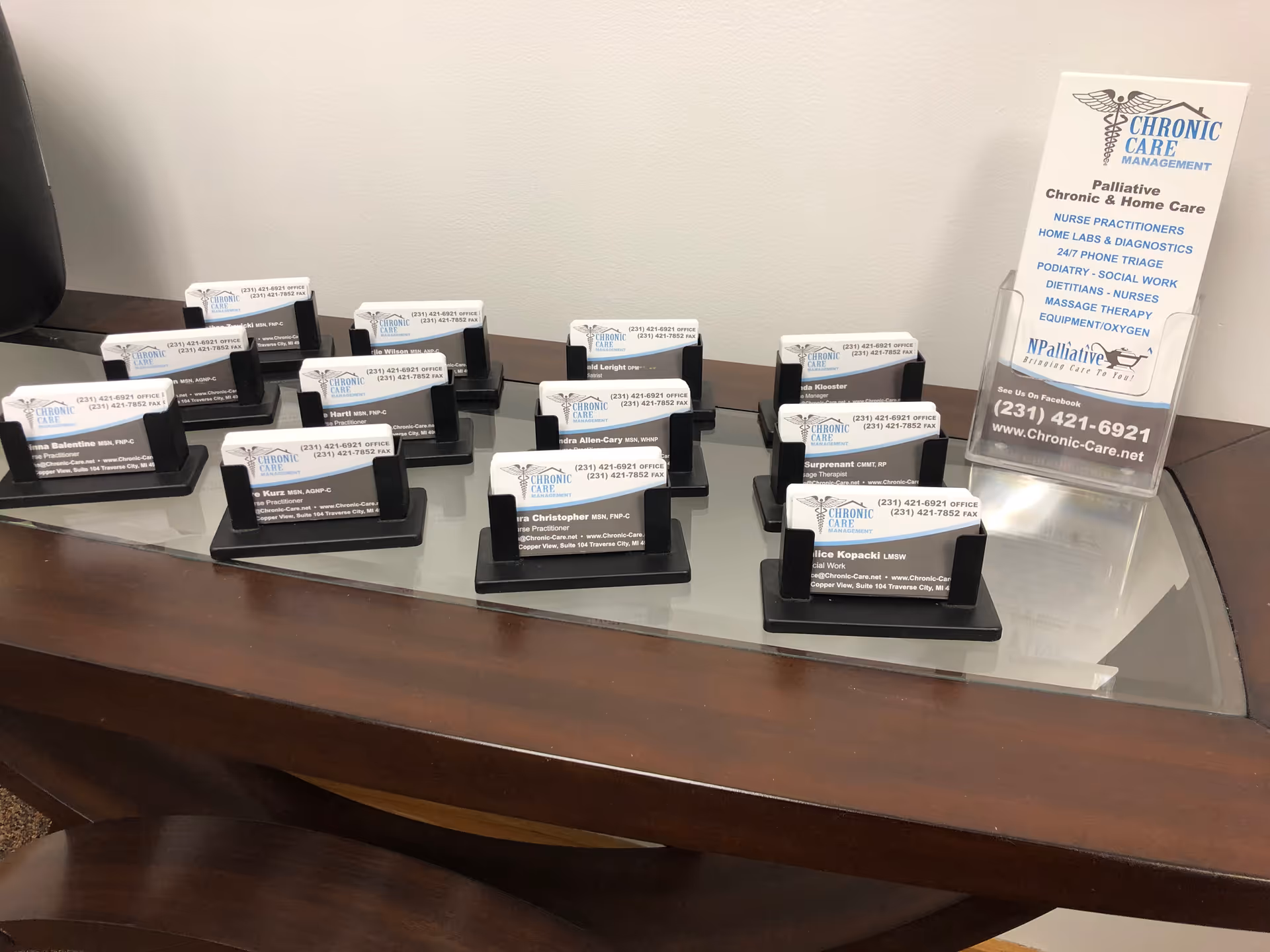 Reception desk with multiple nameplate holders and a brochure on a curved glass surface.