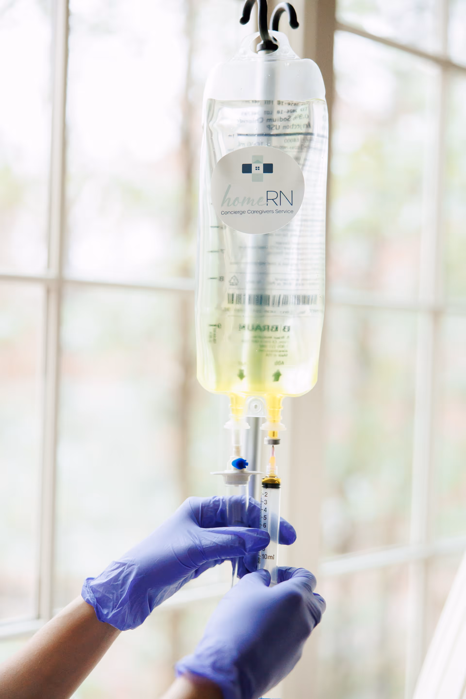 IV drip bag labeled homeRN and gloved hands preparing an infusion in a bright clinic.