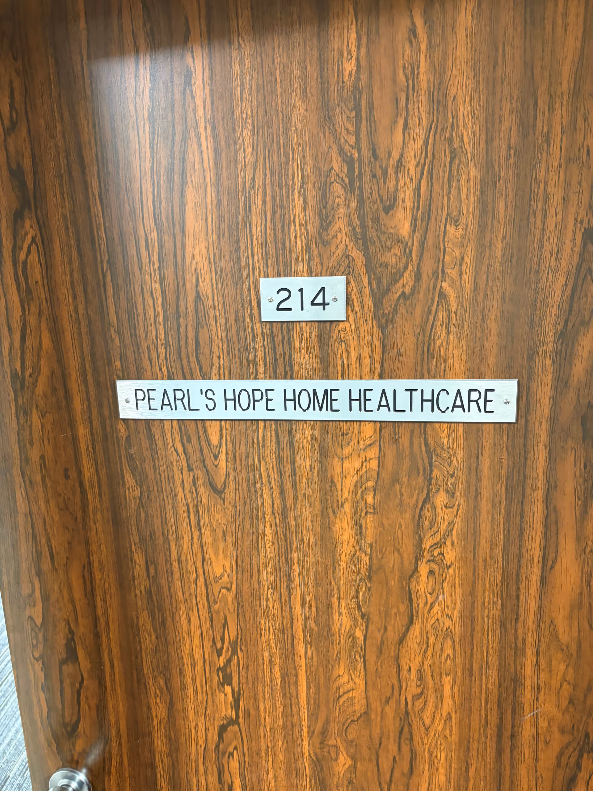 Wooden interior door with room number 214 and Pearl's Hope Home Healthcare sign.