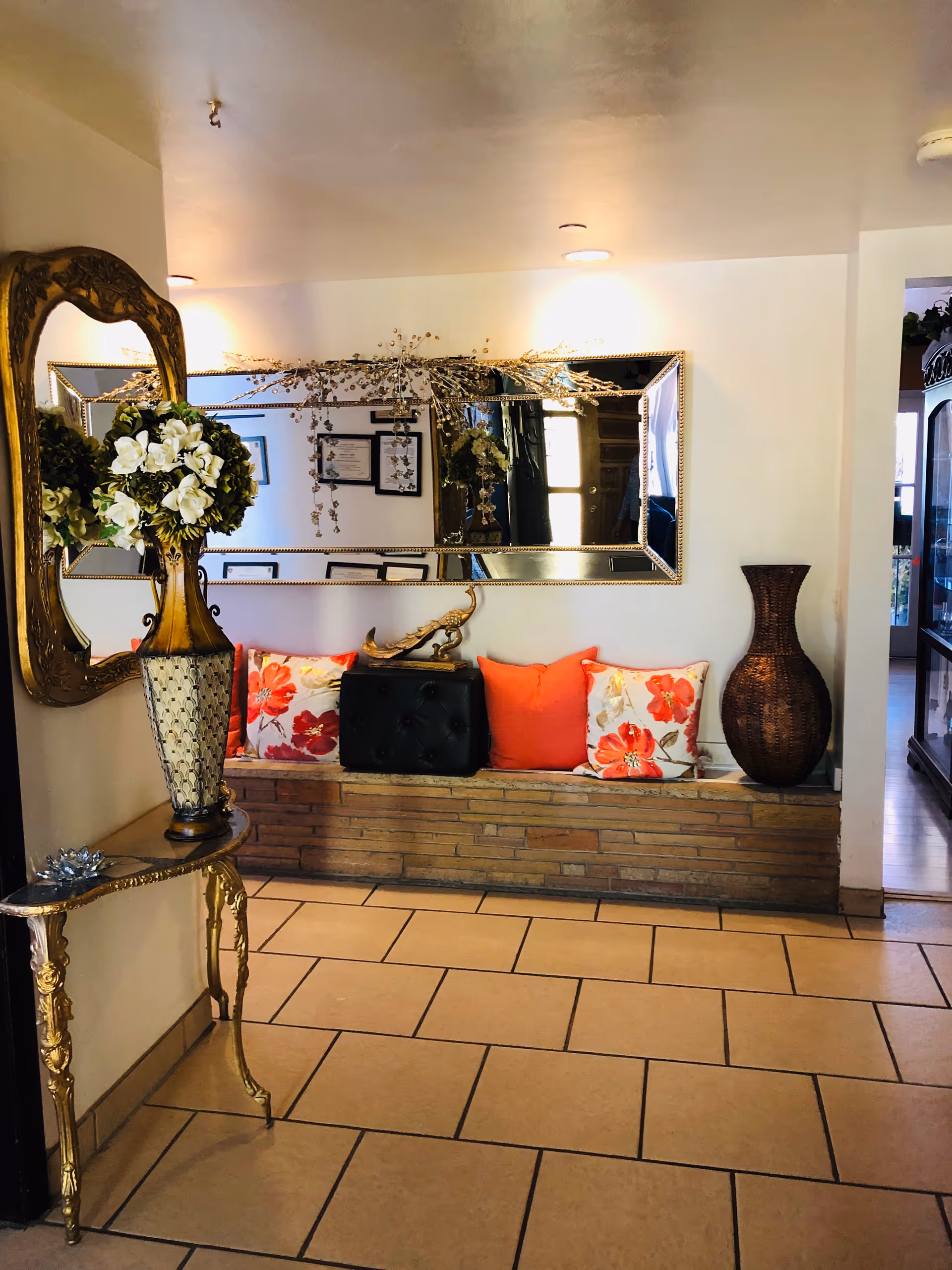 Elegant interior lobby with a bench, floral cushions, large mirror, and vases.