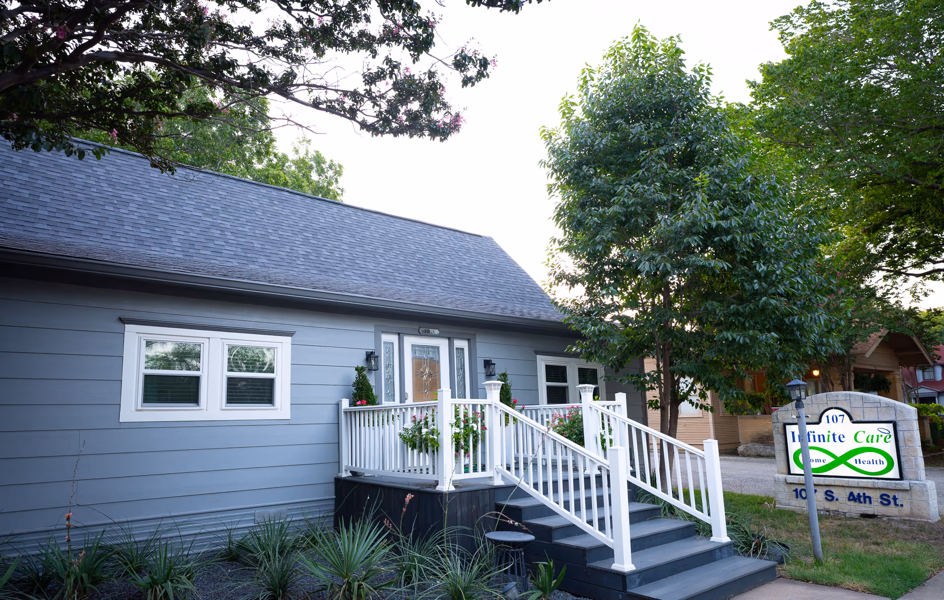 Exterior view of a blue senior care facility with a front porch, stairs, and sign.