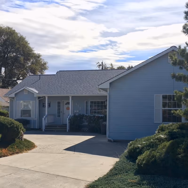 Blue single-story facility with front porch, driveway, and shrubbery.
