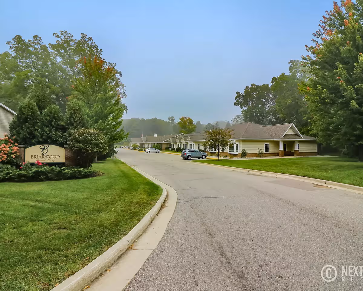 Exterior view of Briarwood Assisted Living & Memory Care with a curved driveway and trees.