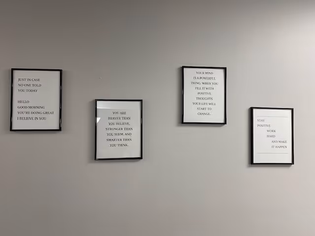 Interior wall with four framed inspirational quotes on gray wall.