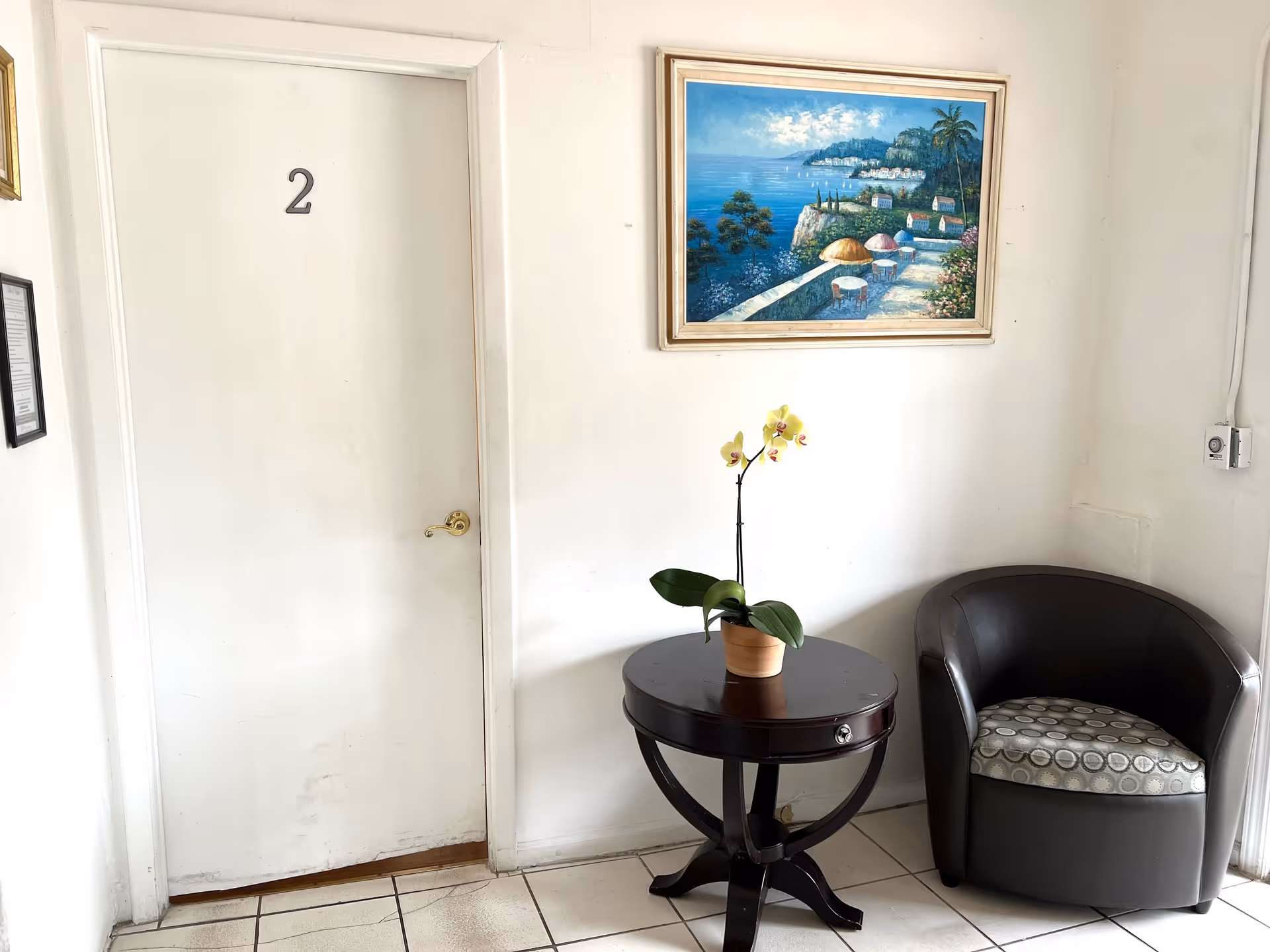 Interior hallway of El Paraiso Home Inc with door 2, round table, plant, and chair.