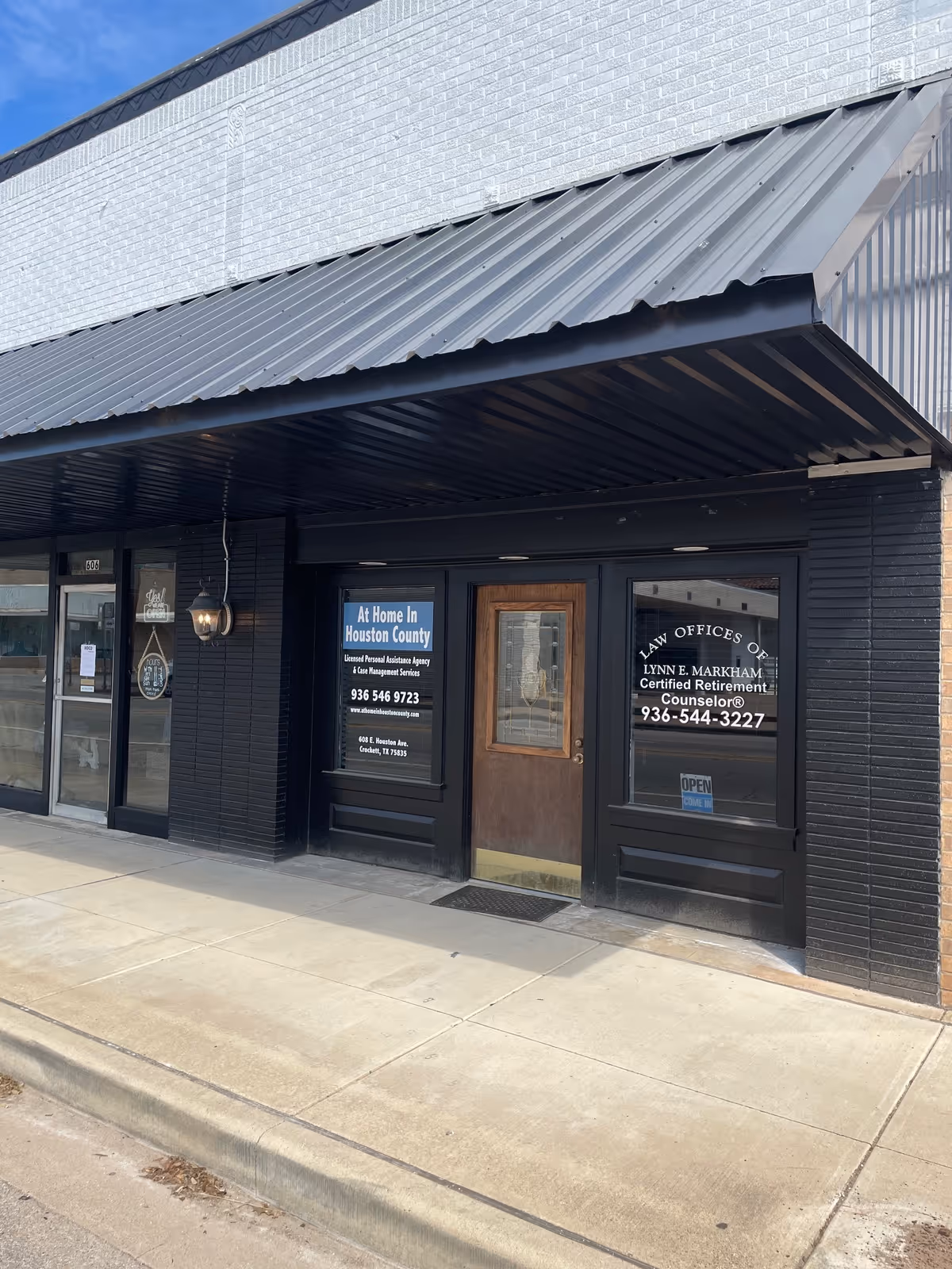 Exterior storefront with black brick, metal awning, and signage for At Home In Houston County.