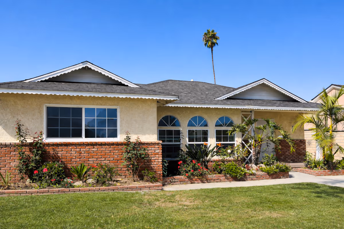 Front exterior of a single-story senior care facility with brick accents and landscaped garden.