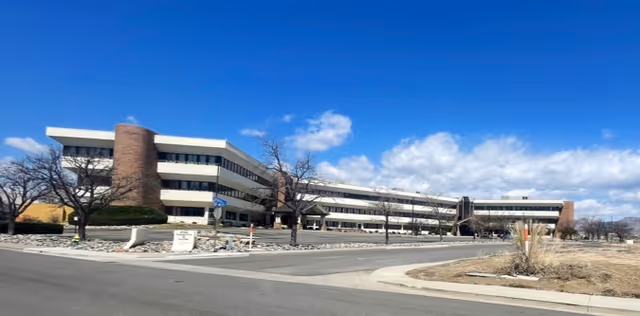 Exterior view of a modern, multi-wing senior living facility against a blue sky.