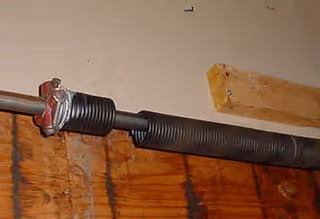 Close-up of a black pipe with a red clamp mounted along a wooden wall.